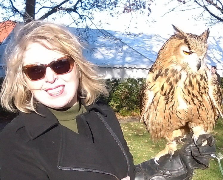 Home page for Liz Cooper craft curator. Image of Liz in sunglasses and coat holding a European eagle owl on her glove.